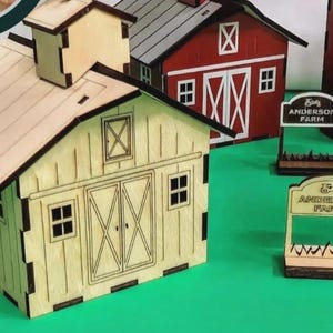 Puede incluir: Miniaturas de madera de edificios de granja, incluyendo un granero, un silo y letreros. El granero es de color claro con un techo oscuro y detalles de puertas. El granero rojo tiene detalles blancos. Los letreros dicen "Anderson Farm".