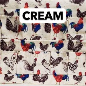 May include: Cream-colored fabric organizer with multiple pockets, featuring a repeating pattern of roosters and hens in red, blue, and black. The word "CREAM" is displayed in a white rectangular box.