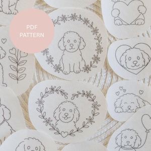 May include: A selection of white fabric patches with embroidered dog designs. Some patches feature dogs inside floral wreaths or hearts. The text "PDF PATTERN" is in a pink circle. The embroidery is in black thread.