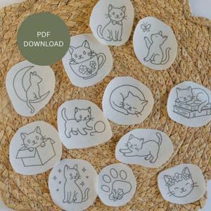 May include: A collection of white fabric patches, each featuring a unique black line drawing of a cat in various poses. Some cats are sitting, playing, or sleeping. The patches are arranged on a woven, light brown surface. Text on a green circle reads "PDF DOWNLOAD".