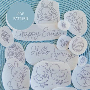 Puede incluir: Un conjunto de parches de tela blanca con diseños bordados con motivos de Pascua y primavera. Incluye conejitos, pollitos, flores, huevos de Pascua y las frases "Happy Easter" y "Hello Spring". Un círculo azul con "PDF PATTERN" está en la parte superior izquierda.