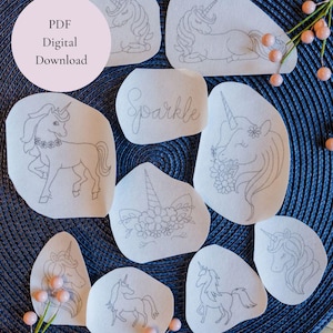 May include: A selection of white, irregular-shaped patches with fine line drawings of unicorns. The designs include various unicorn poses and floral details. The word "Sparkle" is written on one patch. A pink circle with the text "PDF Digital Download" is also present.