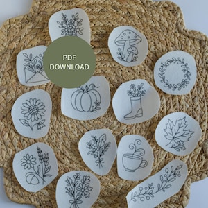 May include: A collection of embroidered patches with various designs, including flowers, a mushroom, a pumpkin, and a maple leaf. The patches are outlined in black thread on a light-colored fabric. A green circle in the center reads "PDF DOWNLOAD".