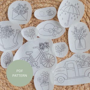 May include: A collection of white fabric patches with delicate gray line drawings of spring-themed images. Designs include flowers, an envelope, a bee, an umbrella, a watering can, a hat, a bicycle, a truck, and a jar. The text "PDF PATTERN" is on a green circle.