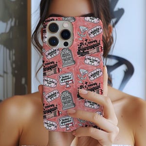 May include: A pink phone case with a repeating pattern of tombstones, martini glasses, and text that reads "Murder Night" and "It's never Mannequin". The case also features the words "Online Detective" and "True Crime Night".