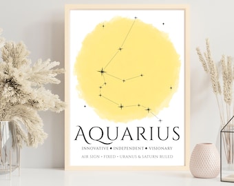 May include: A framed print featuring the Aquarius constellation in black lines against a yellow watercolor background. The word "AQUARIUS" is displayed below, along with descriptive traits. The print is displayed on a white surface.