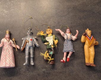 Peut inclure: Ensemble de cinq figurines décoratives des personnages du Magicien d'Oz. Comprend la méchante sorcière, l'homme de fer-blanc, l'épouvantail, Dorothy et le lion. Chaque figurine est peinte de couleurs vives et possède une boucle pour suspendre.
