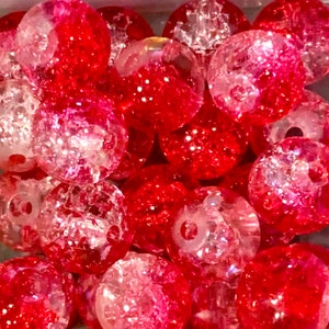 May include: A collection of red and clear glass beads with a sparkly, textured finish. The beads are round and have a hole in the center for stringing.