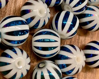 May include: A collection of white and blue striped glass beads. The beads are round with a hole through the center. The blue stripes have a reflective, metallic appearance. These beads are suitable for jewelry making and crafts.