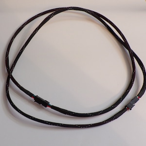 May include: Black and red braided cable with two black connectors. The cable is approximately 1 meter long.