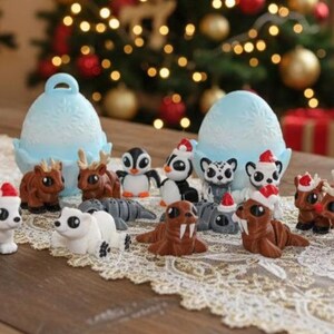 May include: A collection of Christmas-themed animal figurines, including polar bears, penguins, reindeer, and walruses, each wearing a Santa hat. The figurines are arranged on a lace runner with a Christmas tree and candles in the background.