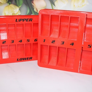 May include: Two red plastic trays with compartments labeled "UPPER" and "LOWER". The trays are numbered 1 through 6 and 1 through 5.