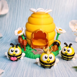 May include: A whimsical scene featuring a yellow beehive with a white flower on top, surrounded by three cartoon bees and flowers. The bees have black stripes, white wings, and smiling faces. The scene is set on a green base.