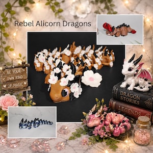 May include: A collection of handcrafted dragon figurines, including a brown and white dragon with flower accents, a white dragon with pink wings, and a blue dragon. The figurines are displayed with decorative elements like books and flowers. The text "Rebel Alicorn Dragons" is visible.