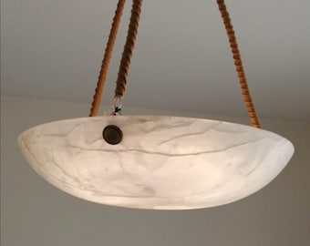 May include: A white, bowl-shaped pendant light fixture with a marbled appearance. The light hangs from two brown rope cords. A circular, bronze-colored button is visible on the underside of the light.