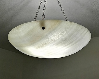 May include: A bowl-shaped pendant light fixture made of translucent, off-white stone with natural veining. The fixture is suspended by three thin metal chains attached to the rim and features a single small circular hole near the top edge.