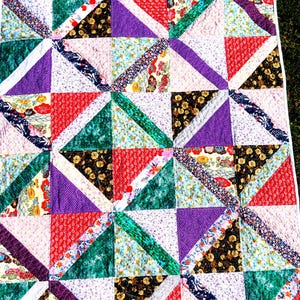 May include: A patchwork quilt with a variety of floral and geometric patterns in shades of red, green, purple, and white.