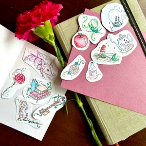May include: A set of 10 watercolor stickers featuring various fairytale and fantasy themes. The stickers are on a white background and include images of a dragon, a rose, a book, a key, a mermaid, a bottle, an apple, a teacup, a vine, and a flower.