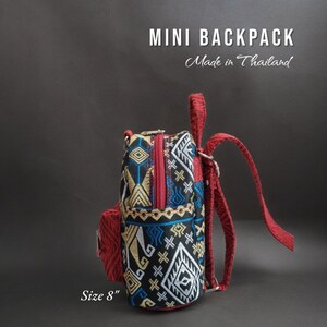 May include: A small red and black patterned mini backpack with a zipper closure. The backpack is 8 inches in size and says "MINI BACKPACK Made in Thailand" on the front.
