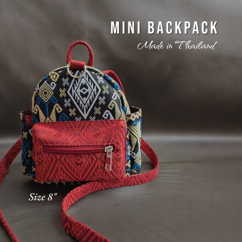 May include: A small red and black patterned backpack with a zippered pocket on the front. The backpack has a red adjustable strap and says "MINI BACKPACK Made in Thailand" and "Size 8" on the bottom.