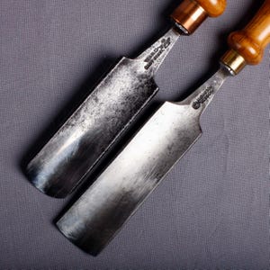 May include: Two antique wood carving chisels with metal blades and wooden handles. One chisel has the text "Ward & Co. Cast Steel" and the other has "Edinburgh Glasgow". The tools are set against a gray background.