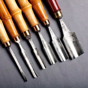 Może przedstawiać: Zestaw trzech ceramicznych kubków z nakrapianym, matowym wykończeniem. Kubki są w odcieniach kremu, jasnoszarym i ciemnoszarym. Każdy kubek ma prosty, minimalistyczny design i zaokrąglony uchwyt.