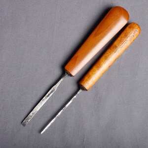 Peut inclure: Deux ciseaux &agrave; bois avec manches en bois. L'un a un manche lisse, brun clair, tandis que l'autre a un aspect plus fonc&eacute; et vieilli. Les lames m&eacute;talliques sont argent&eacute;es et pr&eacute;sentent des signes d'utilisation.