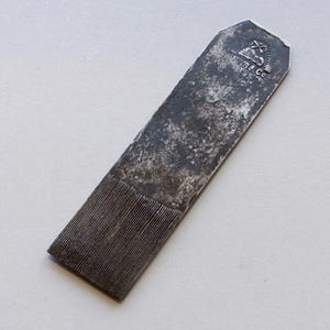 Puede incluir: Una herramienta metálica antigua, de forma rectangular, con una superficie texturizada y estriada en un extremo. La herramienta presenta un aspecto desgastado y envejecido, con el texto "W.H. Myers & Co" visible. Probablemente utilizada para trabajos de carpintería o metalurgia.