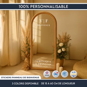 Peut inclure: Un grand miroir en arche avec un cadre doré, affichant le texte "V | F BIENVENUE" et "VERONIQUE & FRANÇOIS - 23 JUILLET 2025". Le miroir est entouré de compositions florales et de bougies. Le texte "100% PERSONNALISABLE" est en haut.