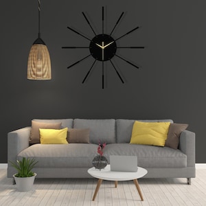 Puede incluir: Un sof&aacute; gris con cojines amarillos y marrones se encuentra frente a una pared gris con un reloj negro con manecillas doradas. Una mesa peque&ntilde;a con un jarr&oacute;n de flores y un port&aacute;til se encuentra frente al sof&aacute;.