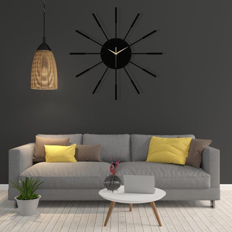 Puede incluir: Un sof&aacute; gris con cojines amarillos y marrones se encuentra frente a una pared gris con un reloj negro con manecillas doradas. Una mesa peque&ntilde;a con un jarr&oacute;n de flores y un port&aacute;til se encuentra frente al sof&aacute;.