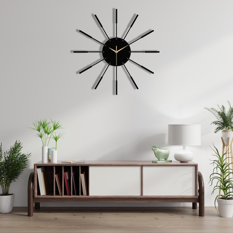 Puede incluir: Un reloj negro con agujas doradas y fondo negro. El reloj tiene un dise&ntilde;o moderno con radios negros delgados que irradian desde el centro.