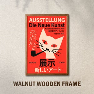 May include: A framed poster with a red background and a white cat with red eyes smoking a pipe. The poster is titled "AUSSTELLUNG Die Neue Kunst" and features the text "K&uuml;nstler der Neuen Welt" in German and "新世界のアーティスト" in Japanese. The poster also includes the text "BERLIN 展示 TOKIO" and "新しいアート" in Japanese. The frame is made of walnut wood.