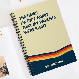 May include: A yellow spiral notebook with the text "THE TIMES I WON'T ADMIT THAT MY PARENTS WERE RIGHT" in blue. The notebook has a blue, orange, yellow, and red striped design at the bottom and the text "VOLUME VIII" in white.