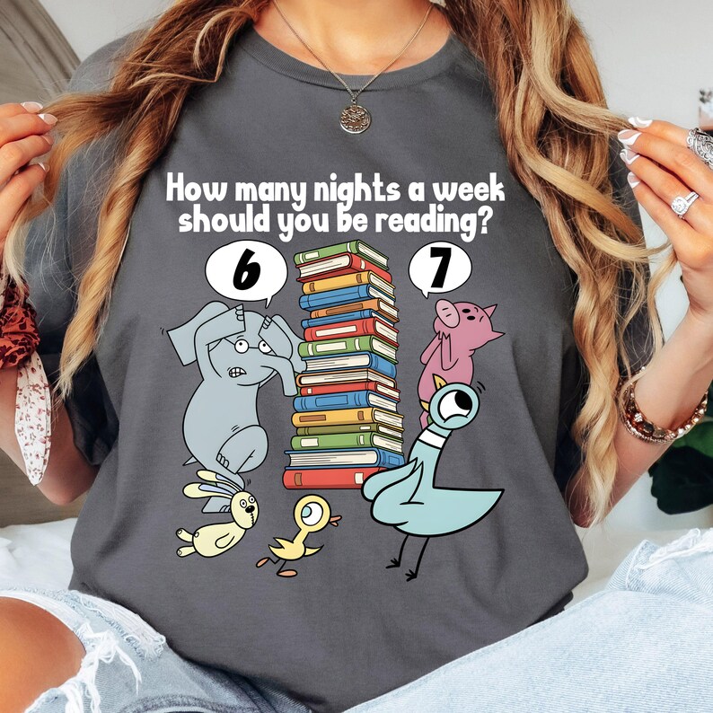 May include: Dark gray t-shirt with the text "How many nights a week should you be reading?" and illustrations of an elephant, pig, pigeon, and other animals. A stack of books is in the center.