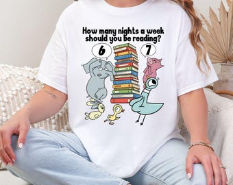 Puede incluir: Camiseta blanca con un gráfico colorido que presenta animales de dibujos animados y una pila de libros. El texto dice: "¿Cuántas noches a la semana deberías leer?" con los números 6 y 7 encima de los animales.