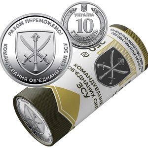 May include: A silver coin with a shield design featuring crossed swords and the text "КОМАНДУВАННЯ ОБ'ЄДНАНИХ СИЛ ЗСУ" in Ukrainian. The coin is in a roll with the text "БАНКНОТНО-МОНЕТНИЙ ДВІР НБУ ОБІГОВА ПАМ'ЯТНА МОНЕТА" in Ukrainian.
