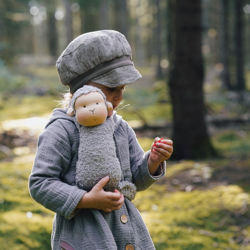 Der Kopf des Schlenkeraffens wird nach der Art einer Waldorfpuppe modelliert. Das Bild zeigt  den Affen, der mithilfe einer Steckfunktion umgehangen und vom Kind getragen werden kann.