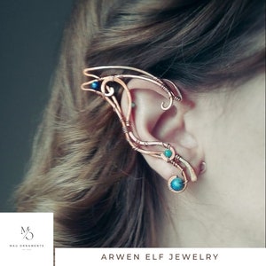 May include: A copper wire ear cuff with blue and green gemstones. The cuff is designed to wrap around the ear and has a delicate, intricate design. Arwen Elf Jewelry.
