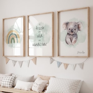 以下が含まれることがあります： 水彩画のイラストが描かれた額装されたプリントが3枚。左側のプリントには、黄色、緑、オレンジの虹が描かれています。中央のプリントは緑色の背景に「Sei frech und wild und wunderbar」というテキストが書かれています。右側のプリントには、緑色の背景にコアラが描かれています。