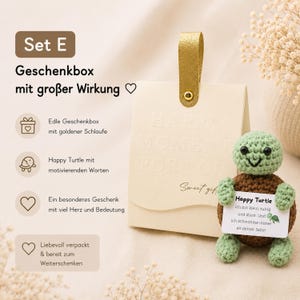 May include: A gift set featuring a cream-colored gift bag with a gold handle and the words "HAPPY MOMENT FOR YOU" embossed on the front. A crocheted green and brown turtle holds a card that reads "Happy Turtle".