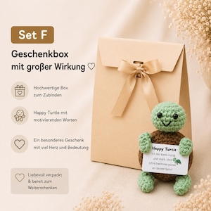 May include: A gift set featuring a tan paper gift bag with a satin ribbon bow, and a crocheted green and brown turtle holding a card. The card reads "Happy Turtle" with a motivational message. The set is designed for gifting.