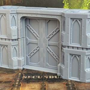 May include: A gray, detailed, plastic model of a double door with two flanking towers. The doors have a cross-hatch pattern and the towers have arched windows.