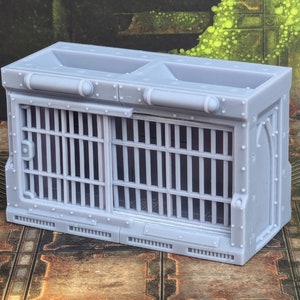 Op de afbeelding: Een grijs, 3D-geprint model van een gevangeniscel met een traliedeur en een klein raam. De cel is ontworpen voor gebruik in een tabletop-spel of een miniatuursetting.