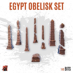 May include: A set of 14 brown miniature obelisks labeled EGYPT OBELISK SET and 14X BITS. The collection includes various upright, broken, and fragmented stone-like pillars featuring carved hieroglyphic symbols on their surfaces, arranged in a group.