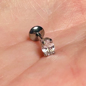 Op de afbeelding: Een zilveren body piercing met een heldere ronde edelsteen.