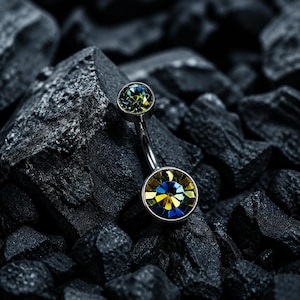 May include: A curved barbell belly button ring featuring a metallic silver-toned shaft with two circular settings. Each setting contains a faceted, multi-colored crystal that shifts between shades of deep blue, vibrant yellow, and bright green.