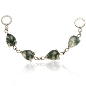May include: A silver chain bracelet with five teardrop-shaped moss agate stones. The stones display green and white patterns. The bracelet has two circular end pieces.
