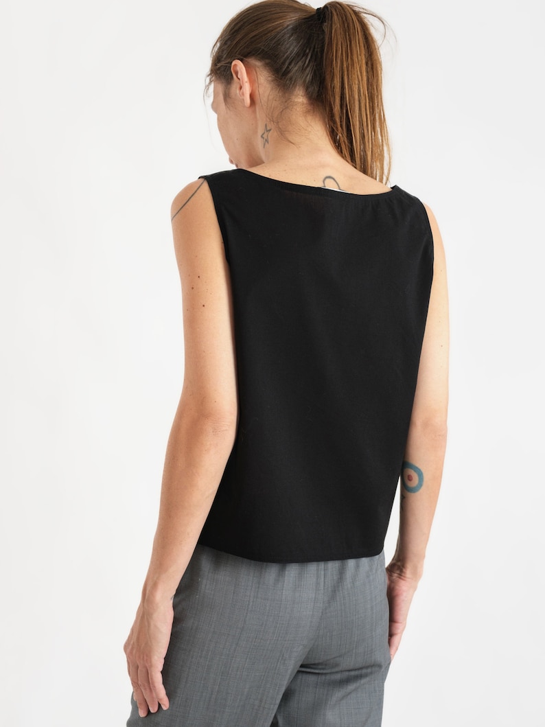 May include: A black sleeveless top with a scoop neck. The top is made of a soft, lightweight fabric and has a relaxed fit.