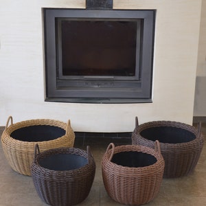 May include: Four wicker baskets, two brown and two beige, with black liners. The baskets are arranged in a semi-circle in front of a fireplace.
